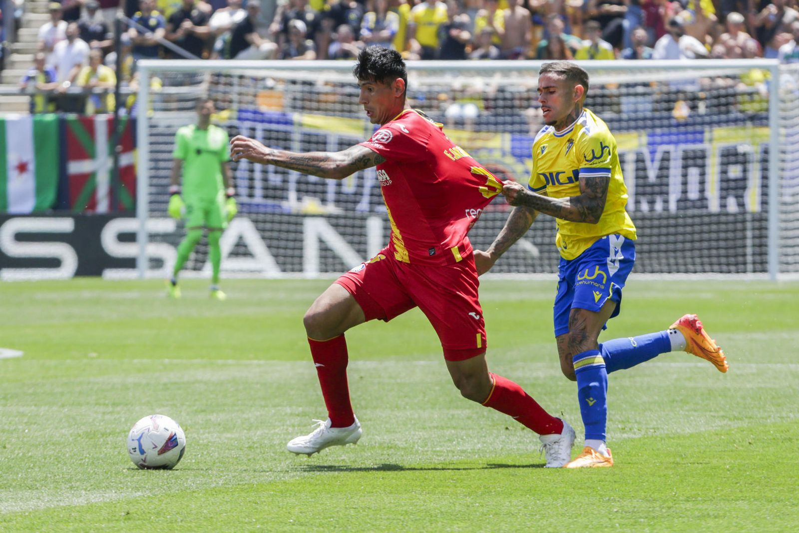 El jugador del Cádiz Roger sujeta de la camiseta a Angileri, del Getafe
