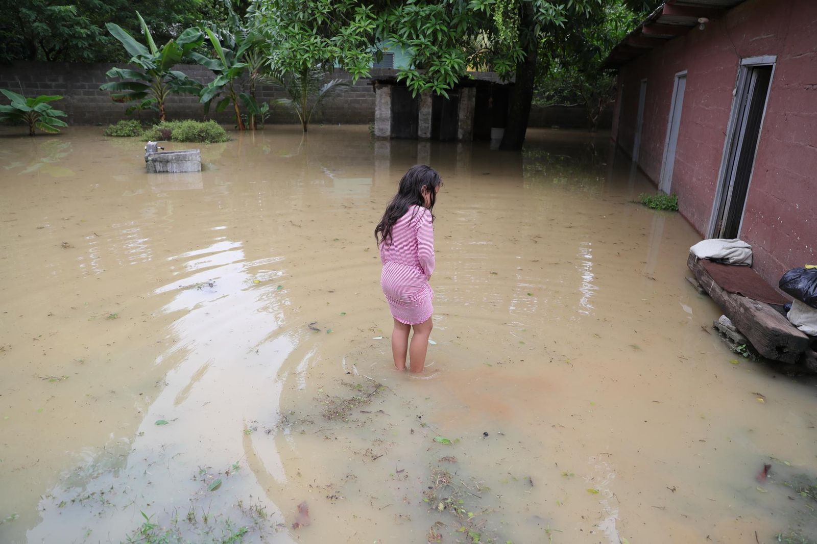 Una niña permanece afuera de su casa inundada hoy, en la ciudad del Progreso (Honduras)