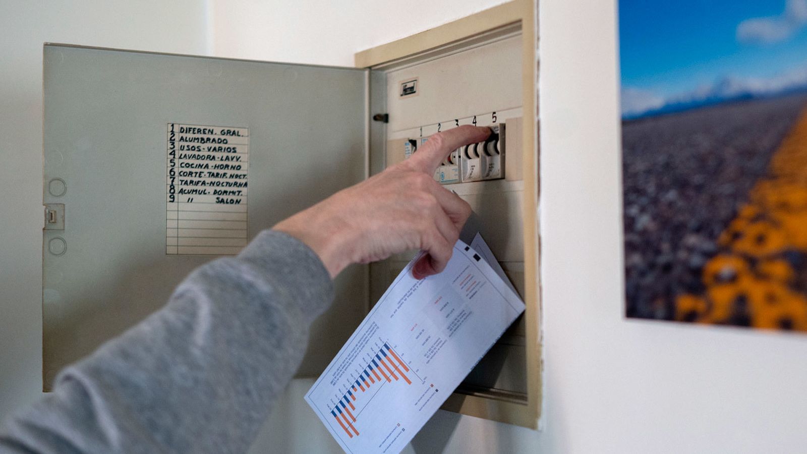 Un hombre sube los plomos de la luz con una factura de luz en la mano, a 3 de enero de 2022, en Madrid