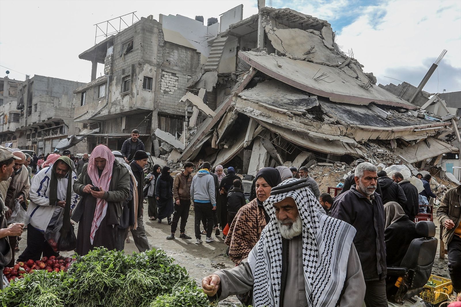 Palestinos hacen compras en un mercado rodeado de edificios destruidos, en Khan Younis,