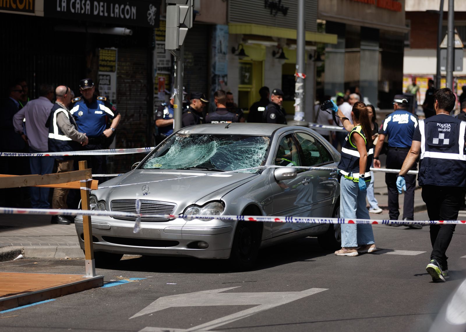 Una agente de la policía nacional toma fotografías del coche con el que han sido atropelladas varias personas, en el Paseo de Extremadura