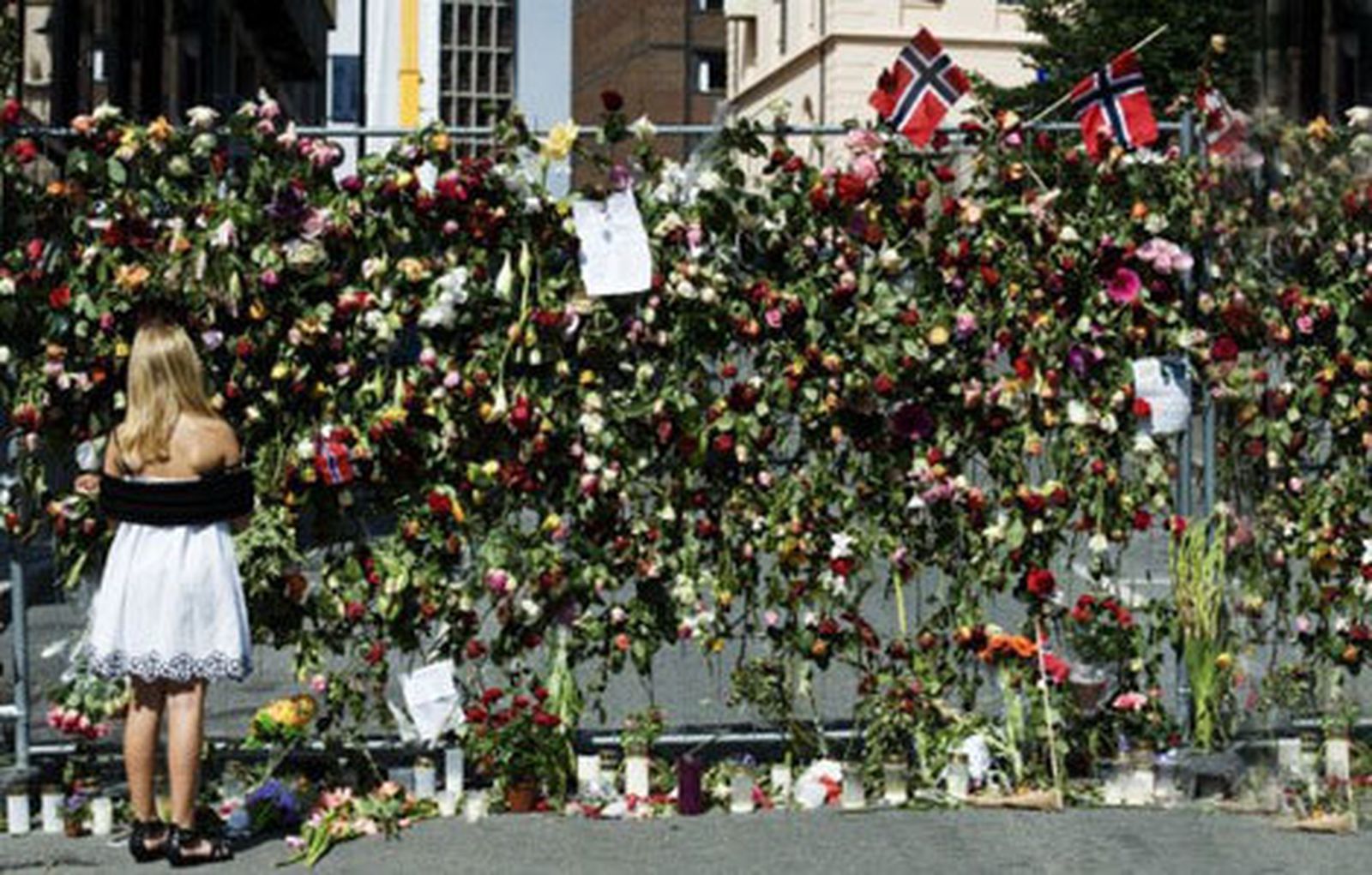 Una joven deposita flores en el muro conmemorativo a las víctimas de los atentados en Noruega