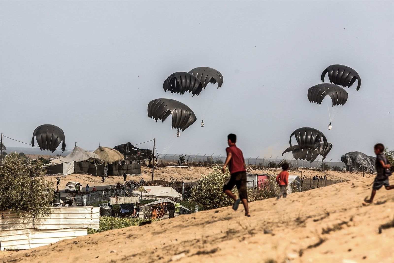 Desplazados palestinos corren a recoger la ayuda internacional lanzada en paracaídas