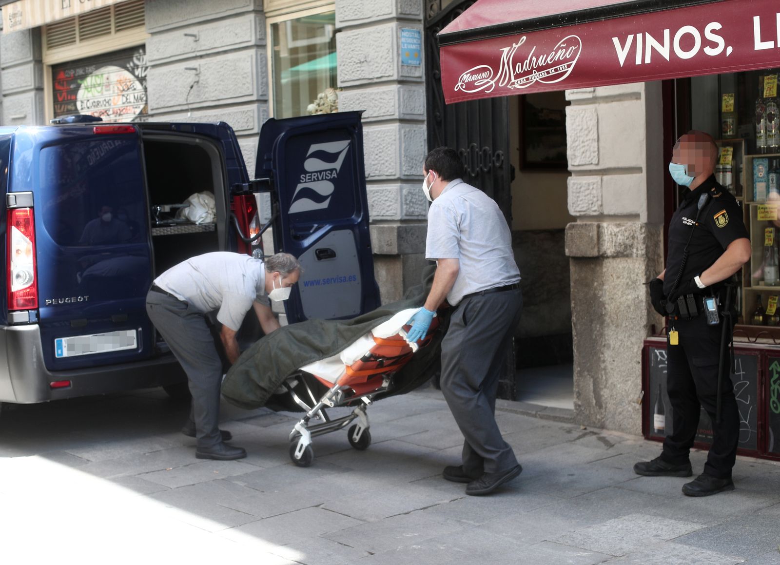 Dos trabajadores de una funeraria recogen los cuerpos sin vida de una mujer y su hijo hallados muertos en un hostal de Madrid