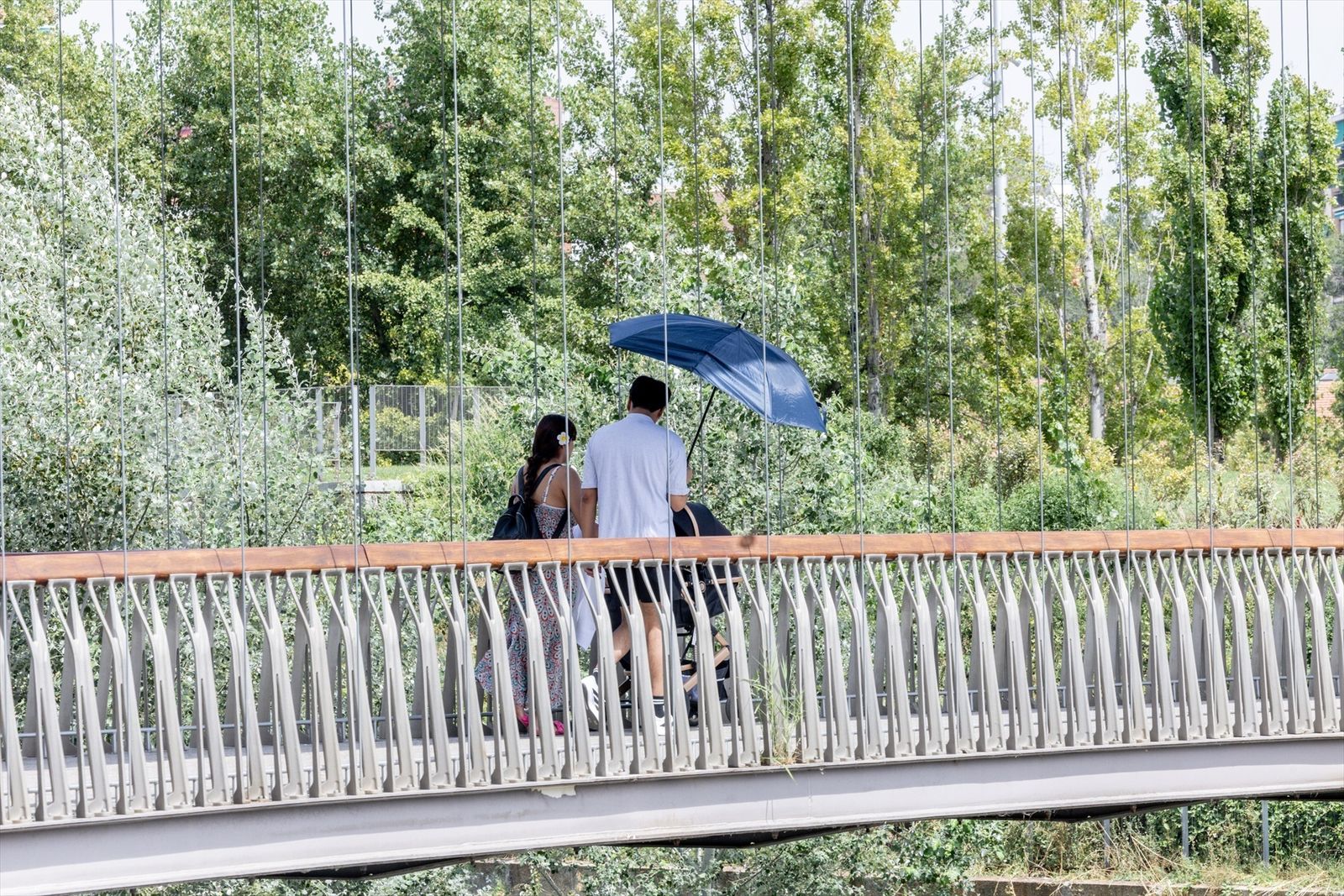 Dos personas se protegen del sol con una sombrilla en Madrid
