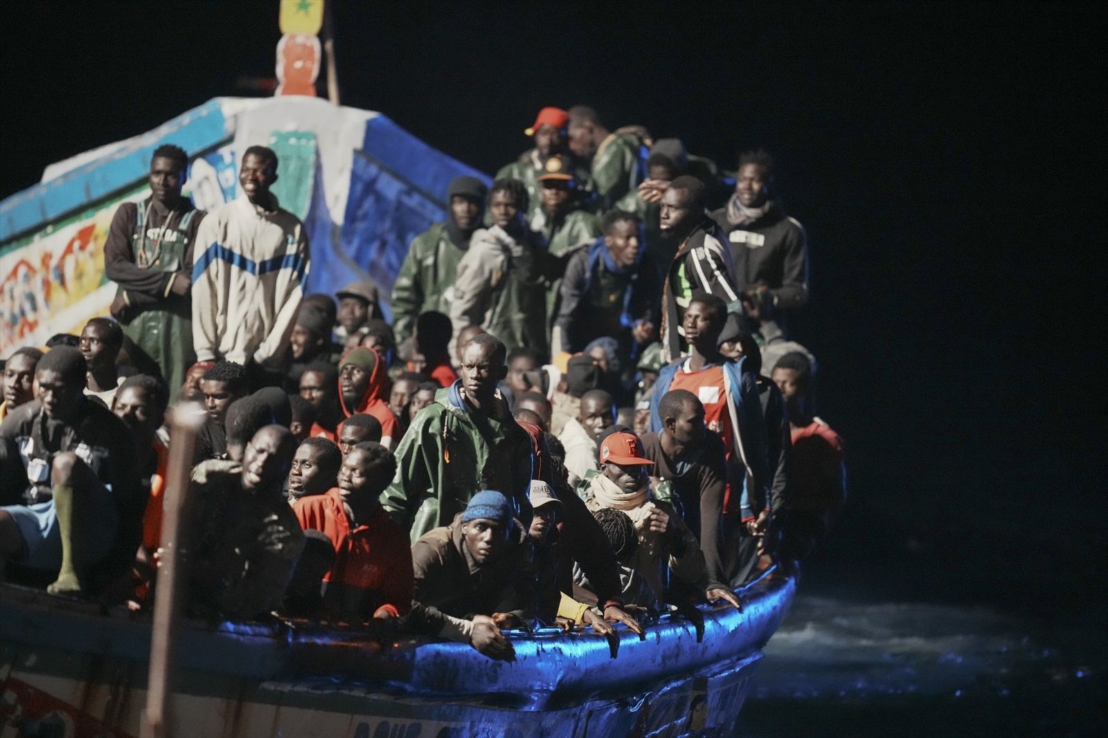 Decenas de personas en un cayuco a su llegada al muelle de La Restinga,