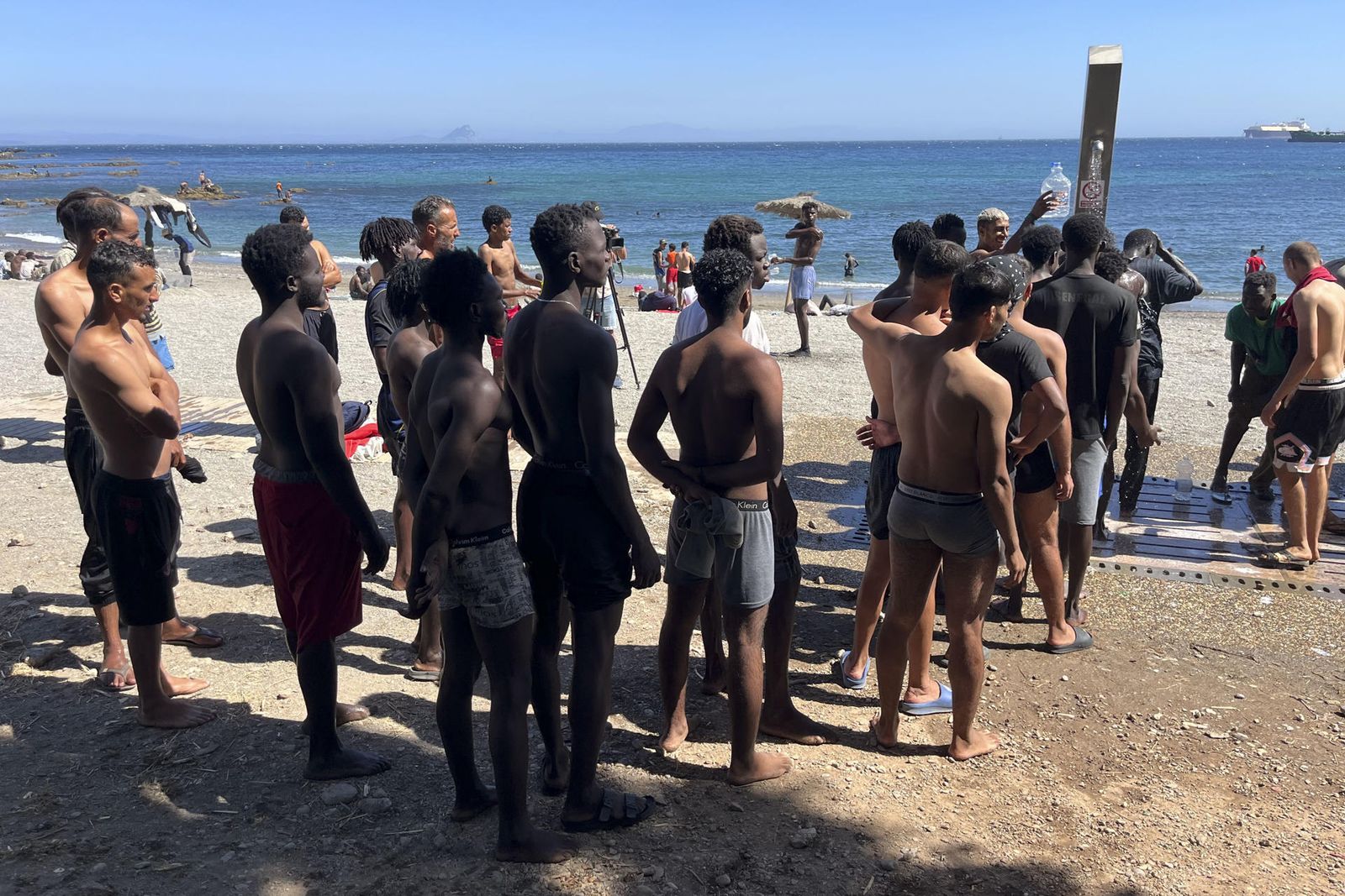 Los jóvenes inmigrantes que duermen en la calle hacen cola para ducharse en la playa del Trampolín, tras acceder a Ceuta