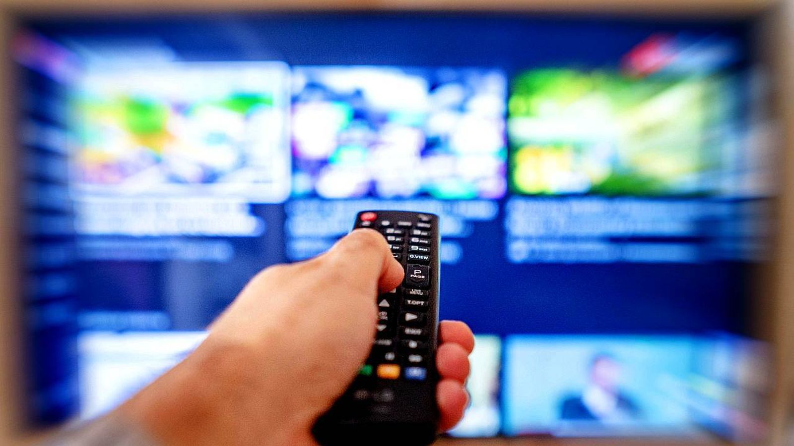 Persona con el mando a distancia delante de la televisión