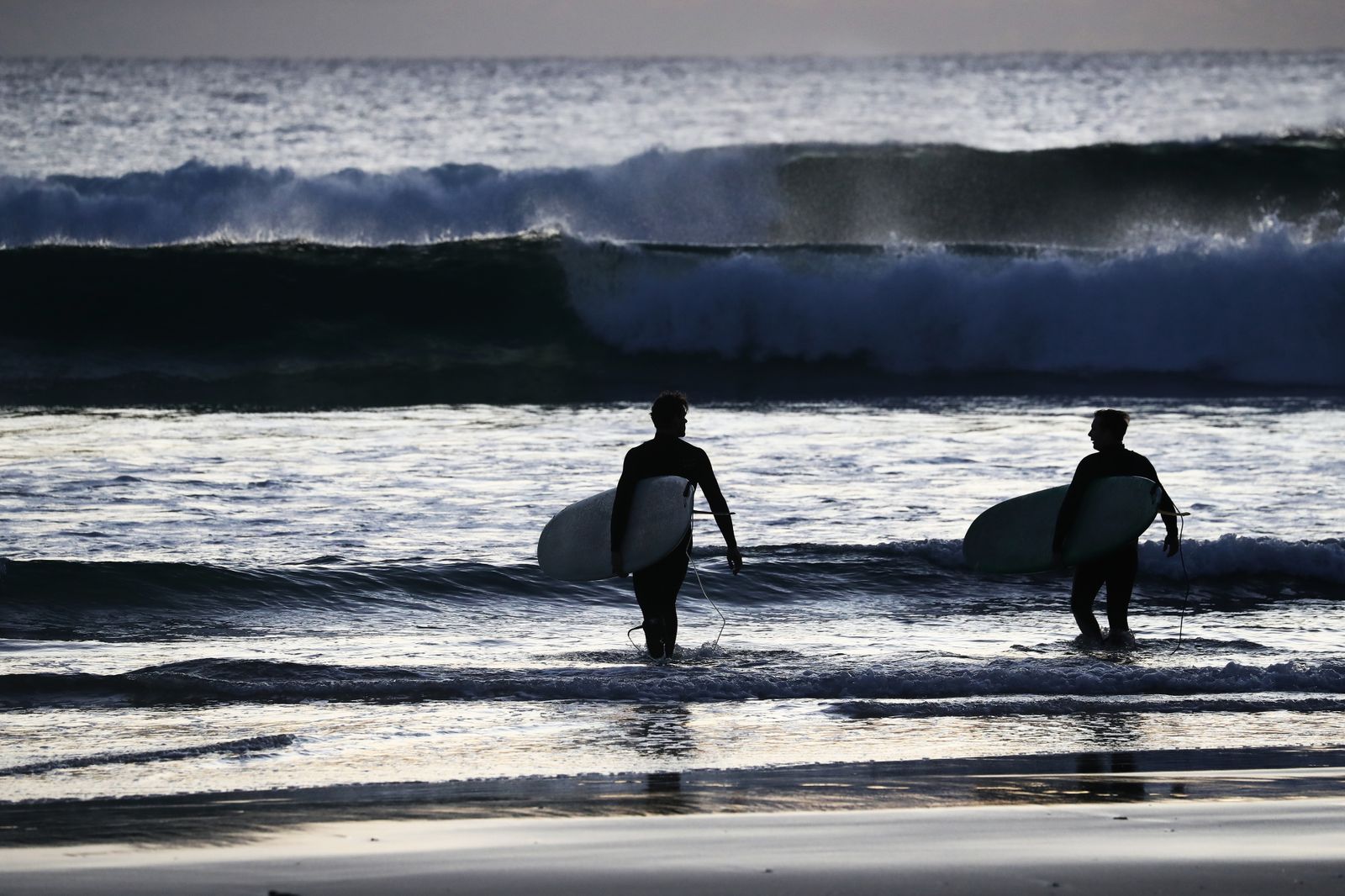 Imagen de dos surfistas en una playa