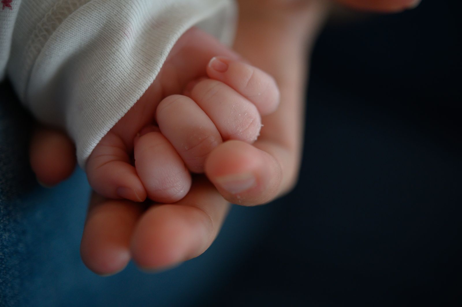Una madre sostiene la mano de su bebé recién nacido de dos semanas.