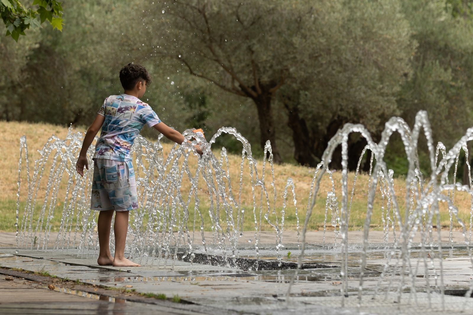 Un niño juega con el agua en Madrid