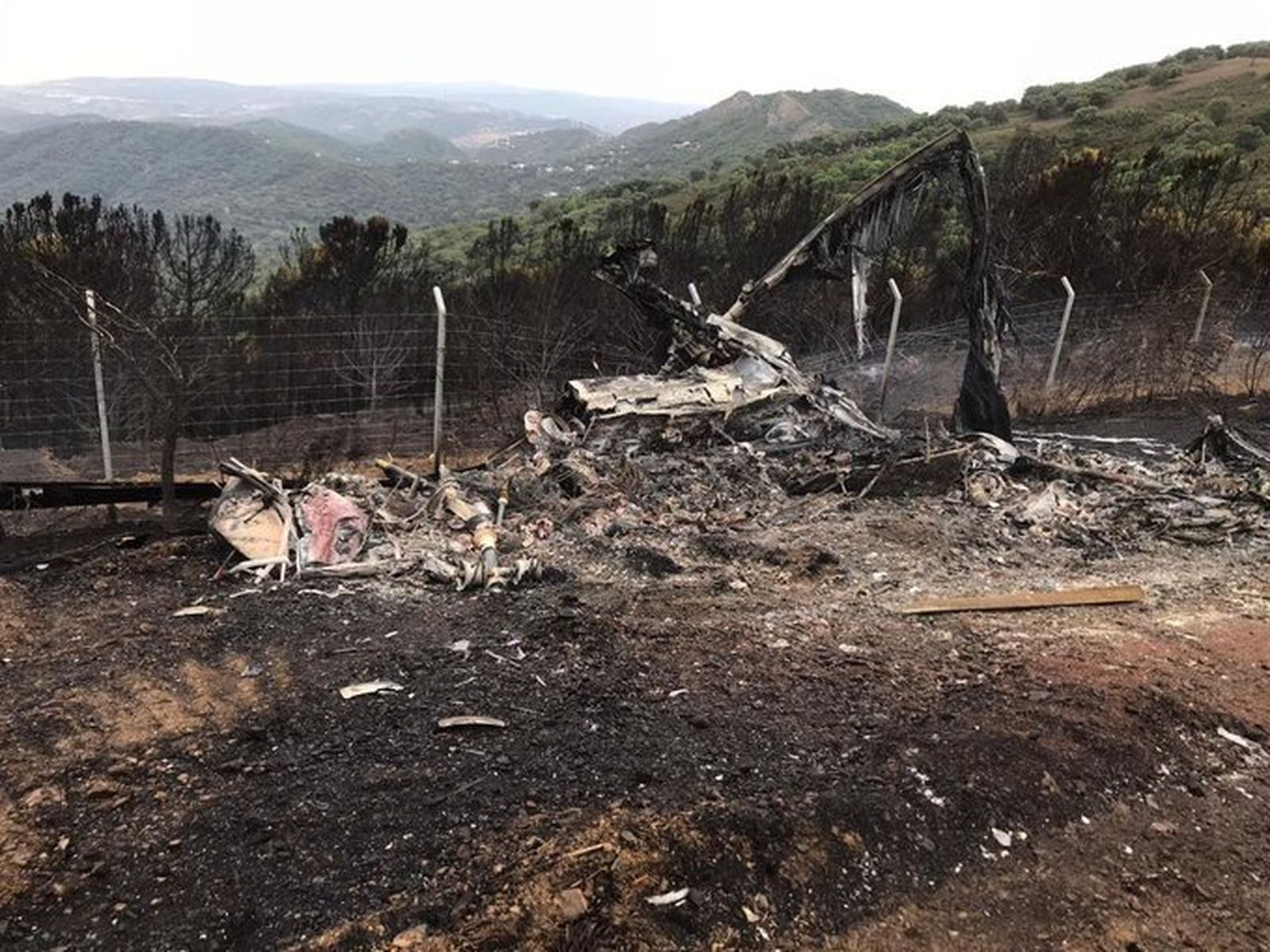 El helicóptero accidentado este lunes, calcinado por las llamas del incendio de Sierra Bermeja