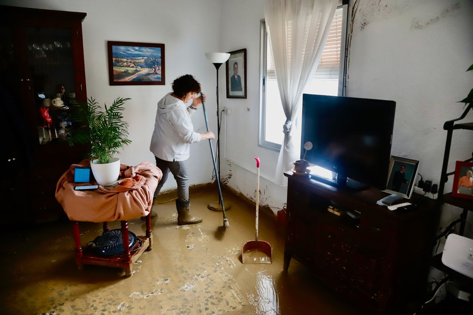 Vecinos de Cártama (Málaga) limpian el salón de casa tras el paso del la Dana