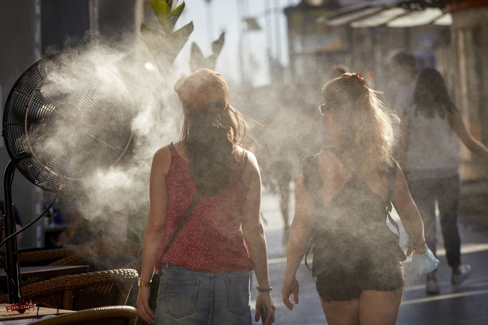 Varias personas caminan al lado de un difusor de vapor de agua de un restaurante de la calle Alcalá