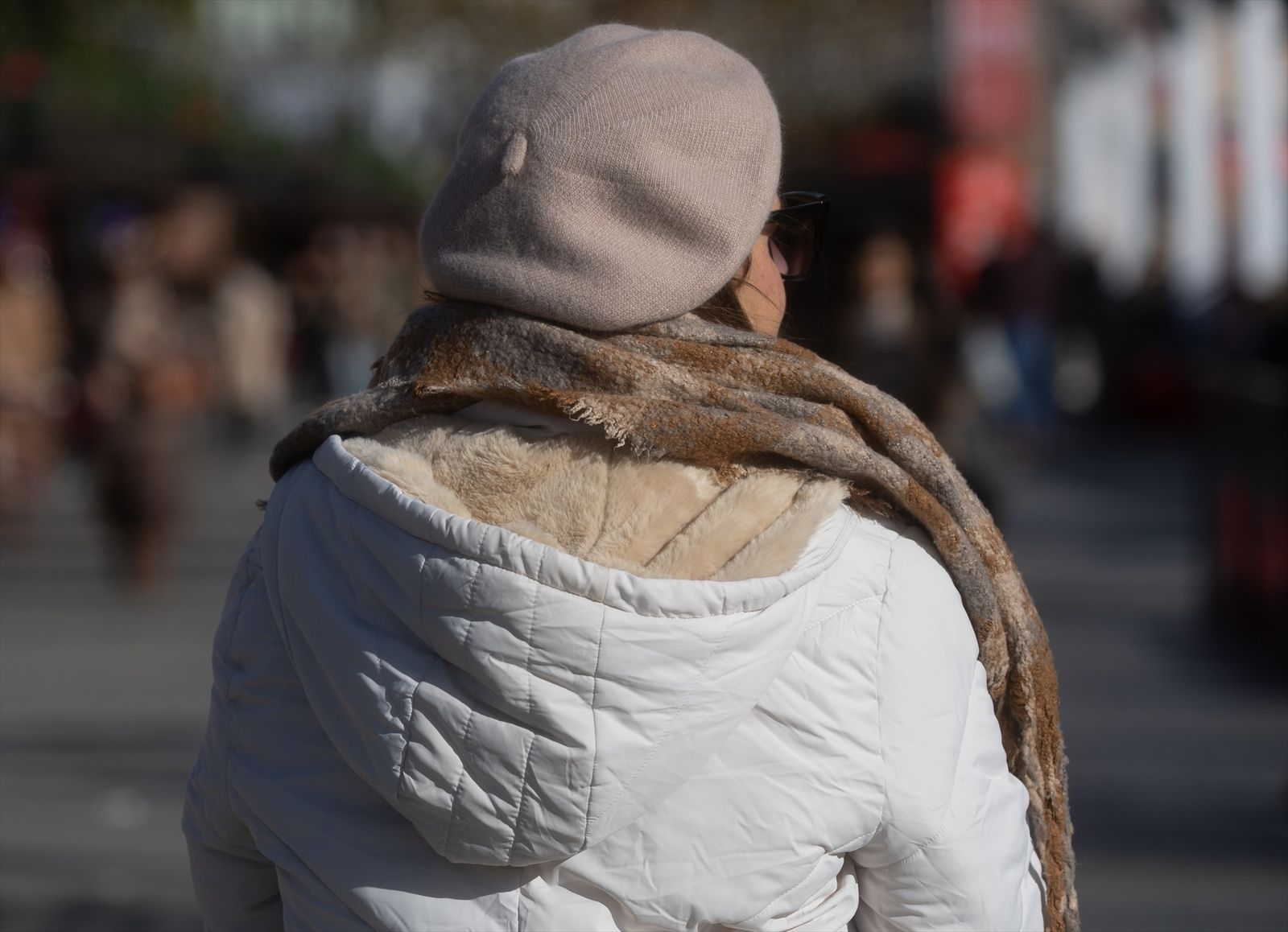 Una mujer abrigada con bufanda y gorro pasea por la ciudad
