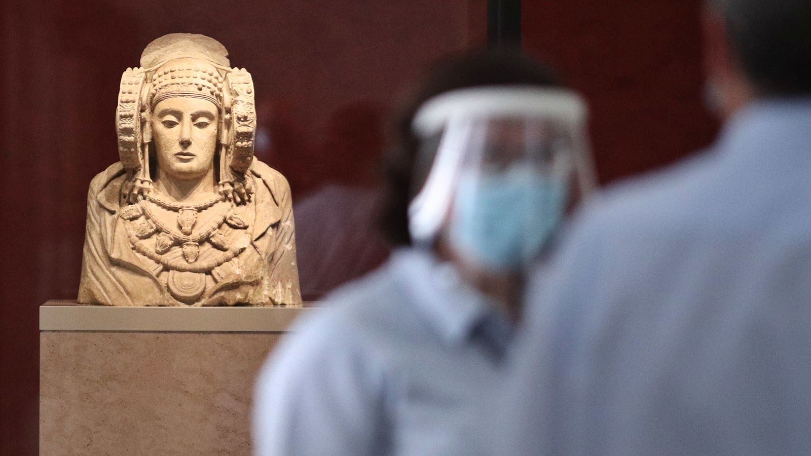 Dos trabajadores protegidos con mascarilla y pantalla vigilan una de las salas donde se encuentra la escultura de La Dama de Elche en el Museo Arqueológico