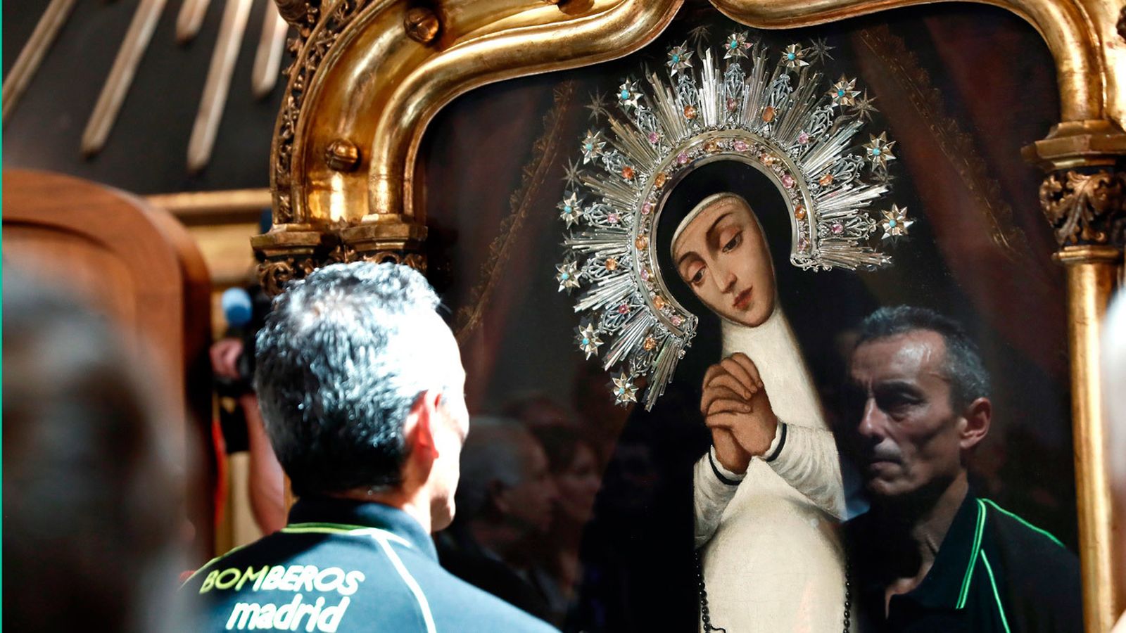 Un bombero frente a al cuadro de la Virgen de la Paloma, patrona de los bomberos, tras el tradicional descendimiento del cuadro