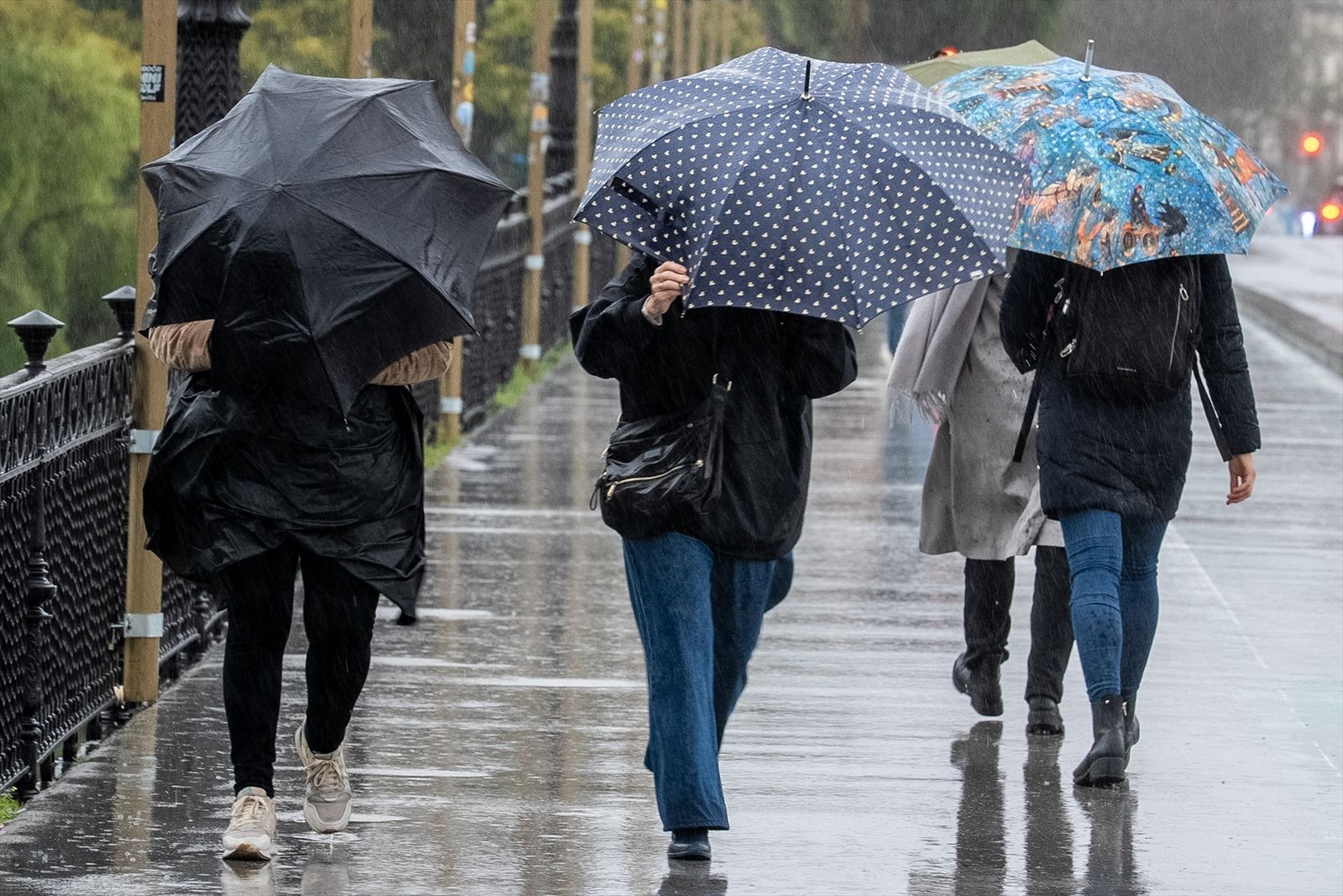 Peatones cruzan el puente de Triana en Sevilla en una jornada marcada por la lluvia y el viento, provocados por el paso de la borrasca Joseph