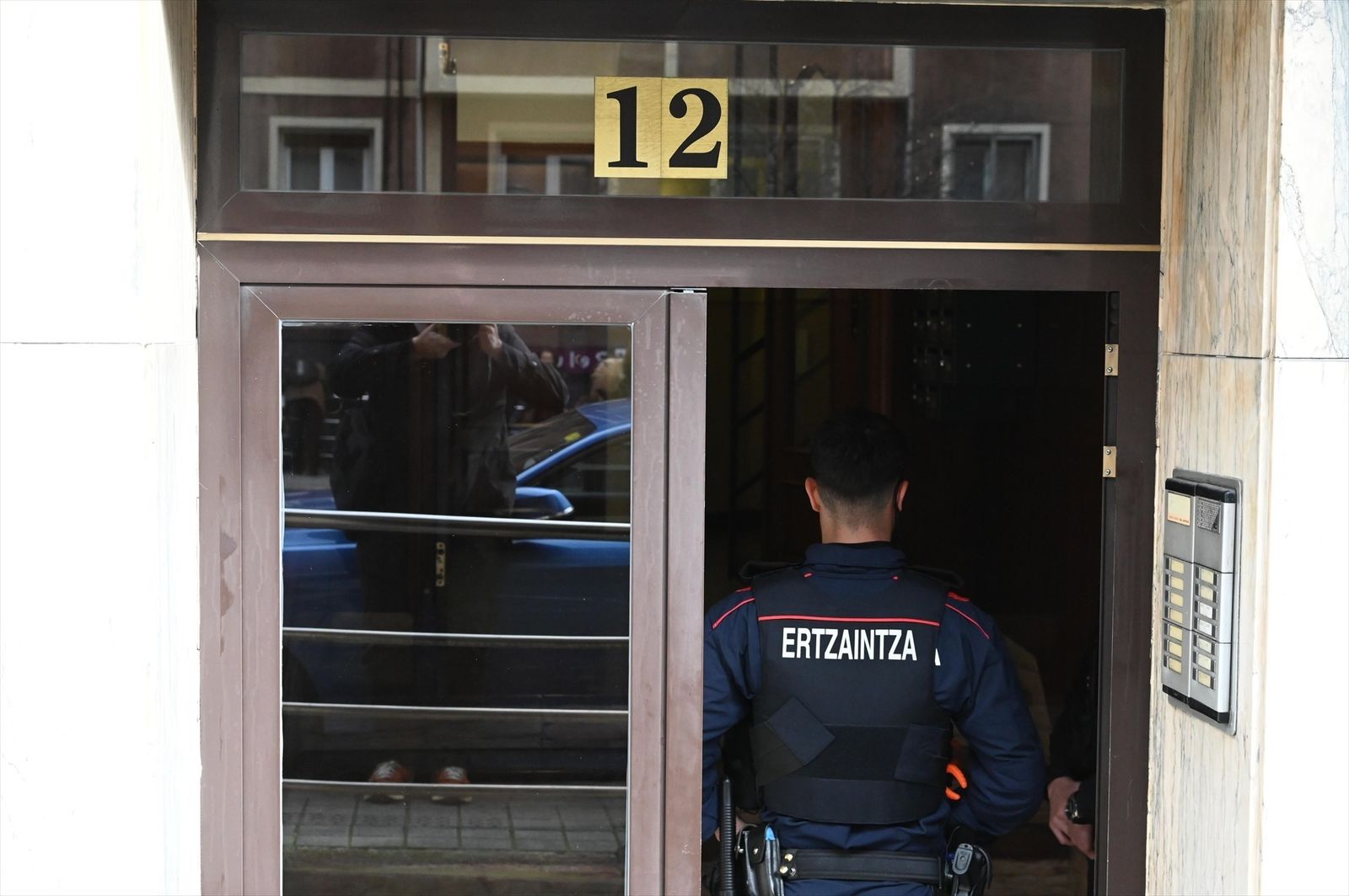 Un ertzaintza entra en el portal de la vivienda donde una mujer ha matado a su pareja