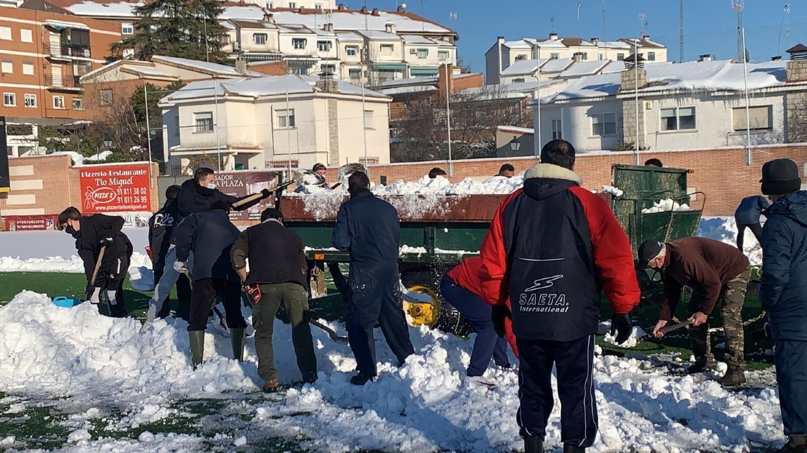 Cargan la nieve en el volquete de un tractor
