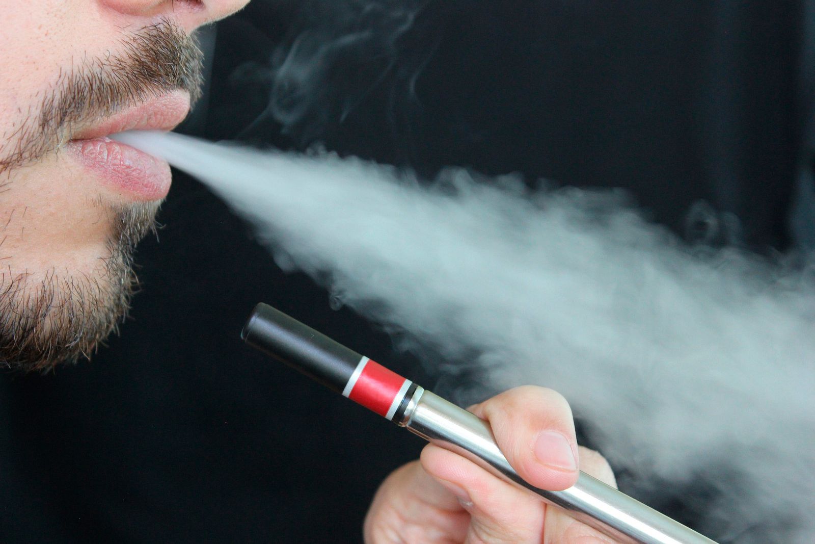 Un joven fuma un cigarrillo electrónico