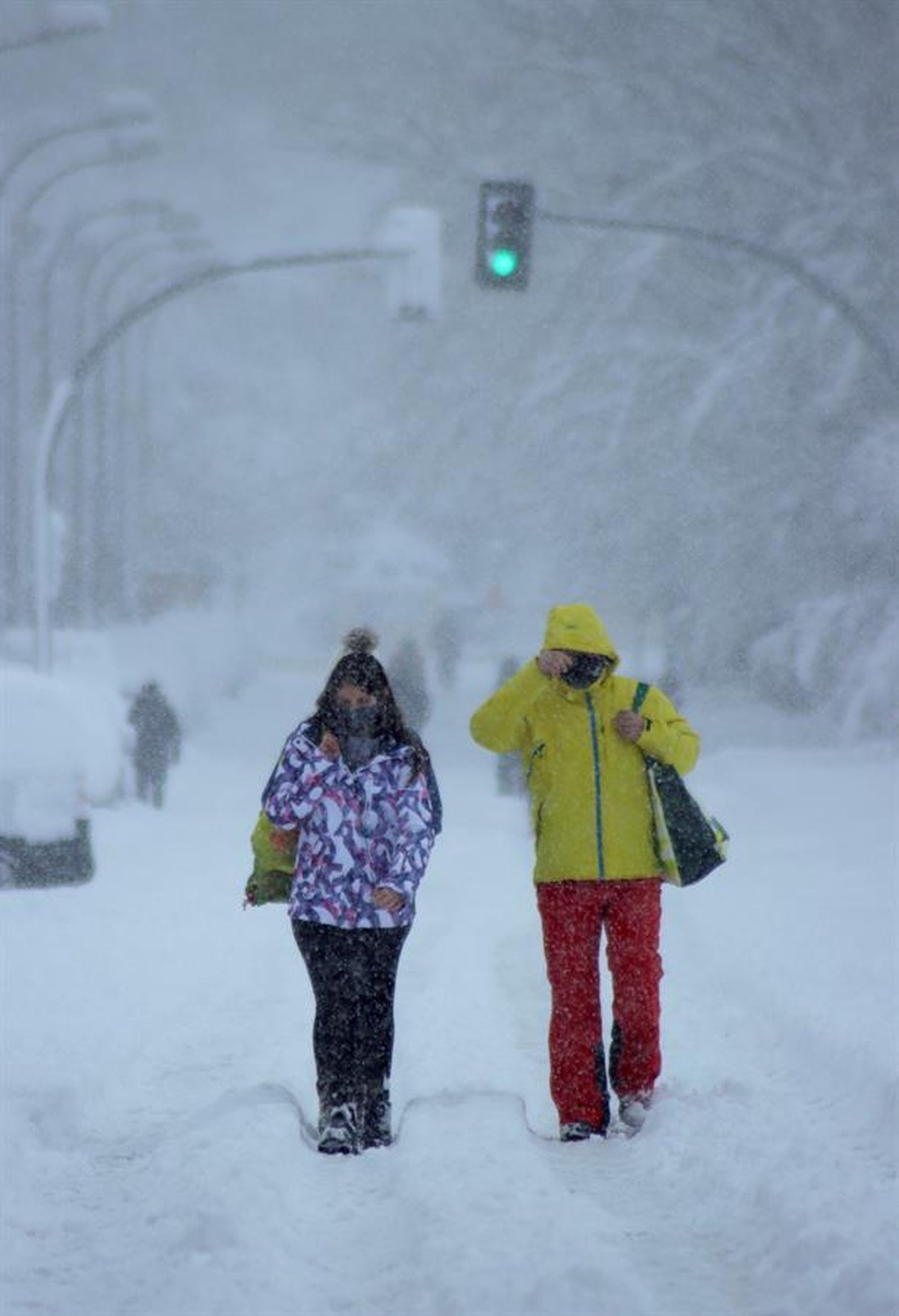 Dos personas caminan por la calle en plena nevada en Madrid