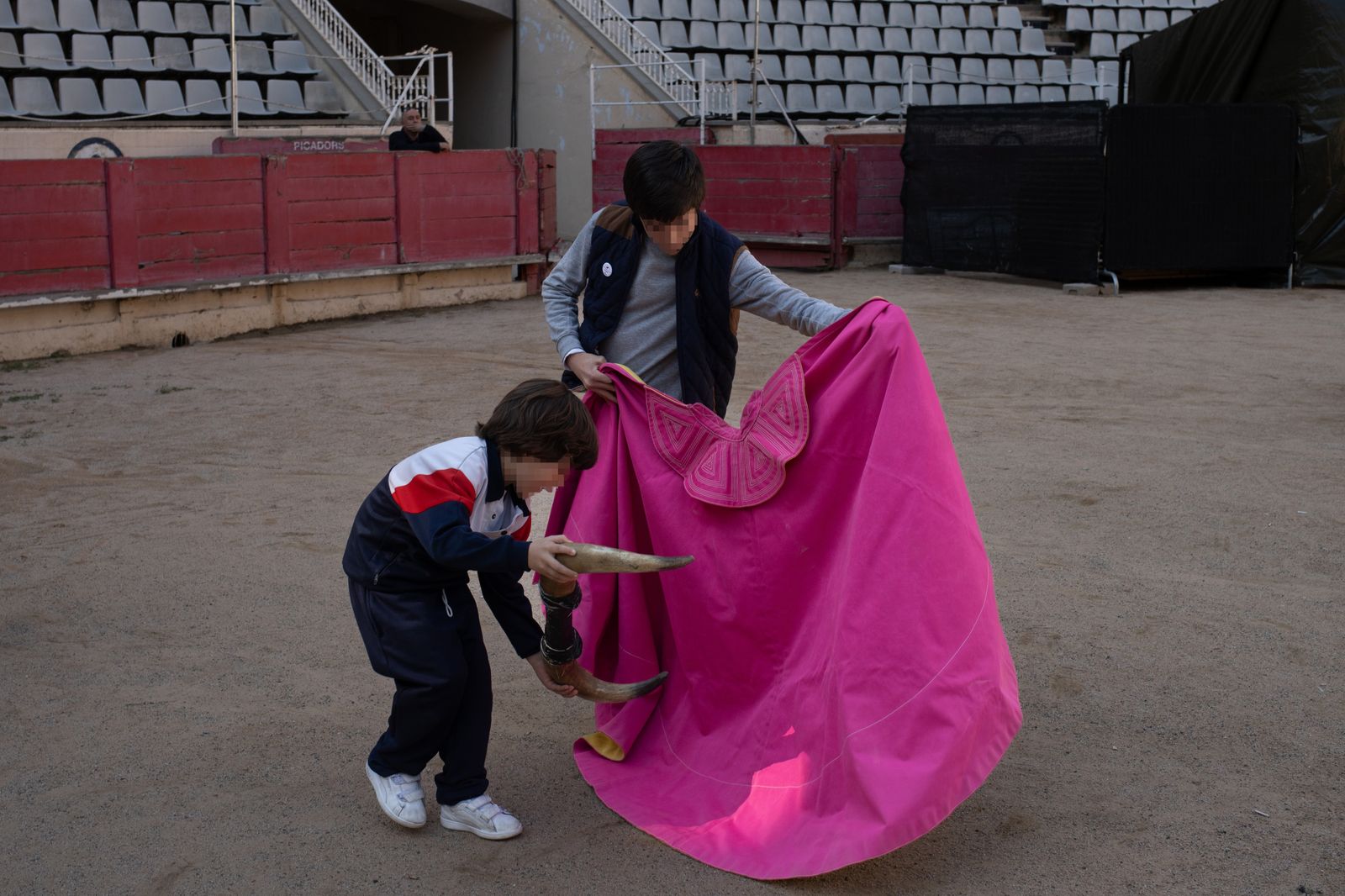 Dos niños juegan con un capote y unos cuernos de toro durante un acto por el Día Internacional de la Tauromaquia, en la Plaza de Toros La Monumental de Barcelona