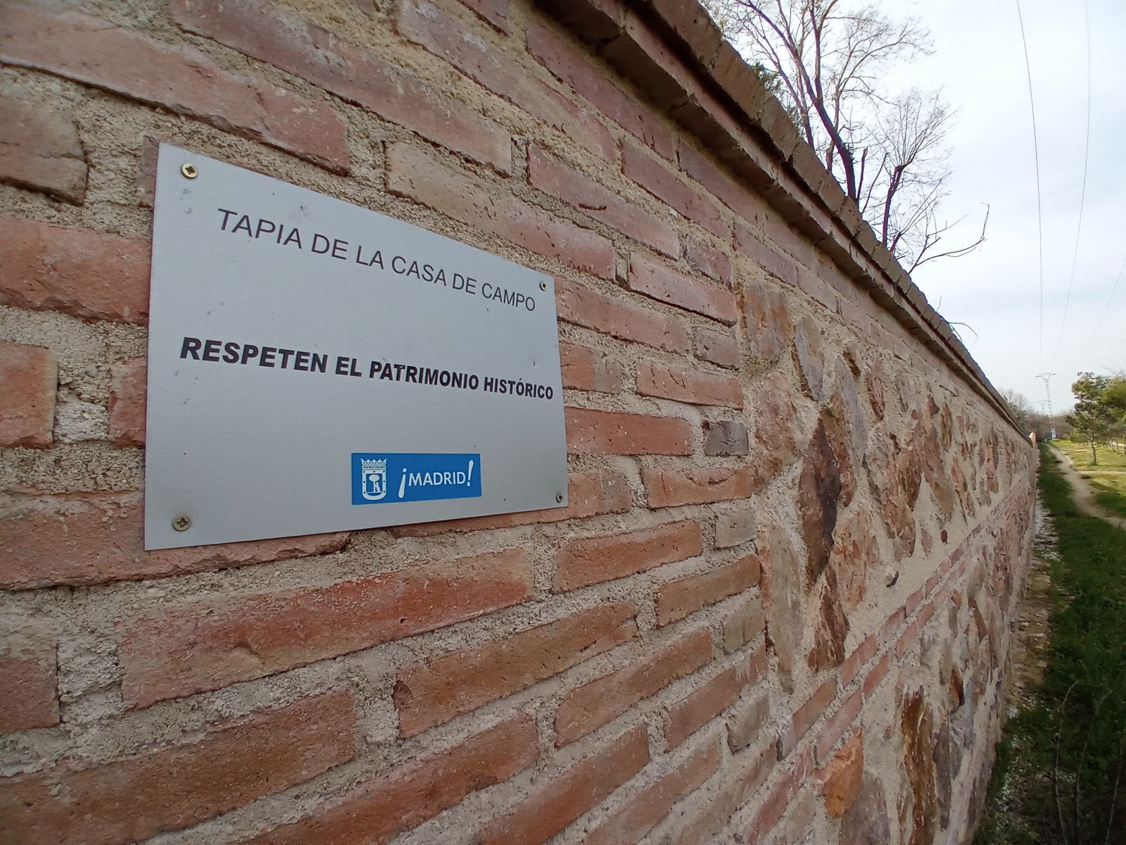 El muro rehabilitado con una placa que indica su protección