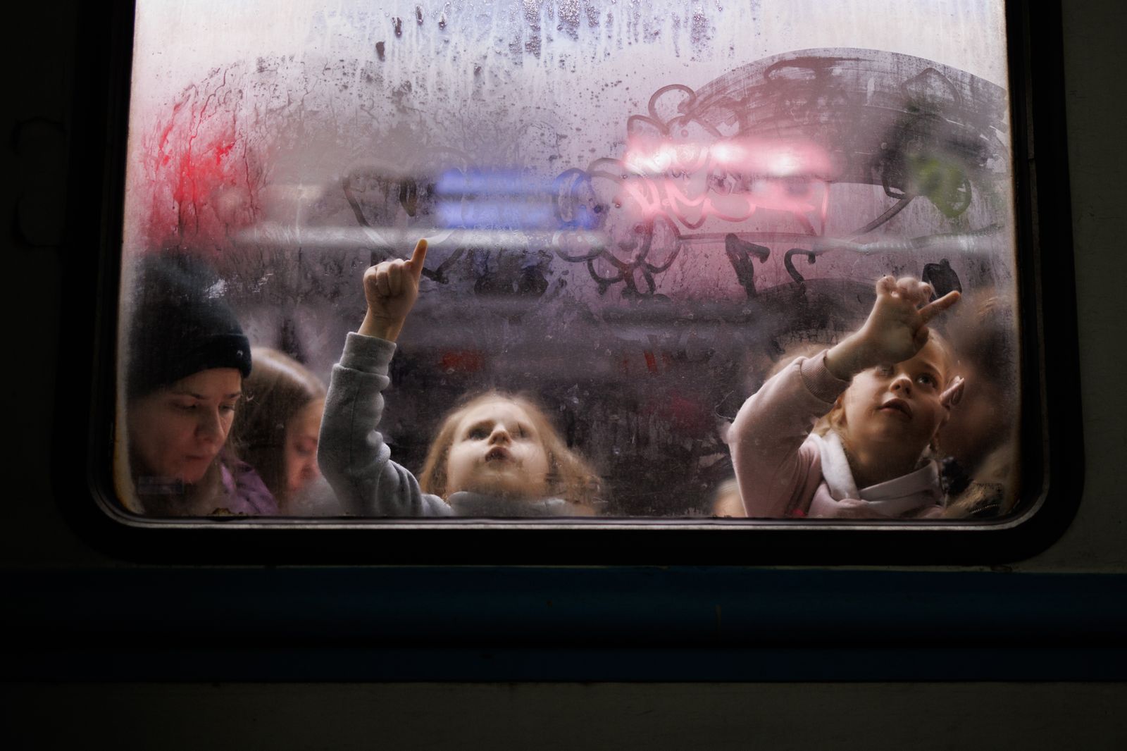 Dos niñas pintan el cristal de uno de los vagones de la estación de tren de Lviv