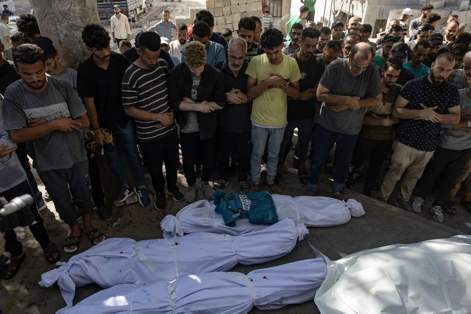 Rezo frente a los cadáveres de las personas muertas en el ataque israelí a una cafetería de la playa de Gaza