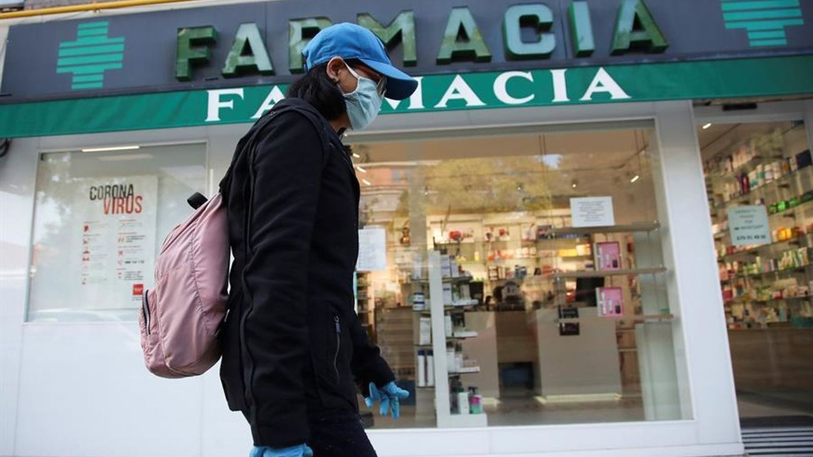 Una persona camina frente a una farmacia