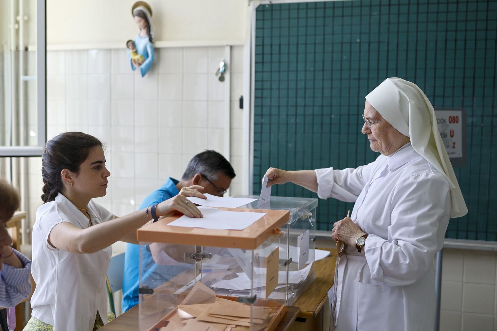 Una monja deposita su voto en una urna durante la jornada electoral del 23J