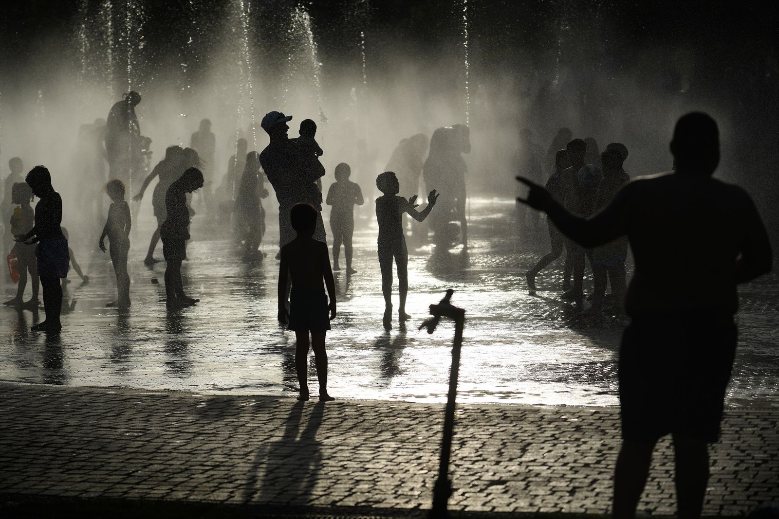 Varias personas, entre ellas niños, se refrescan en los chorros de Madrid Río