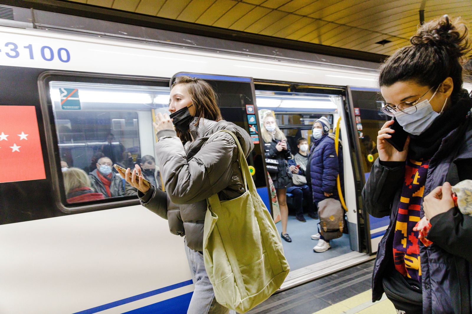 Una mujer se quita la mascarilla tras bajar de un metro en el andén de la estación de Metro de Callao