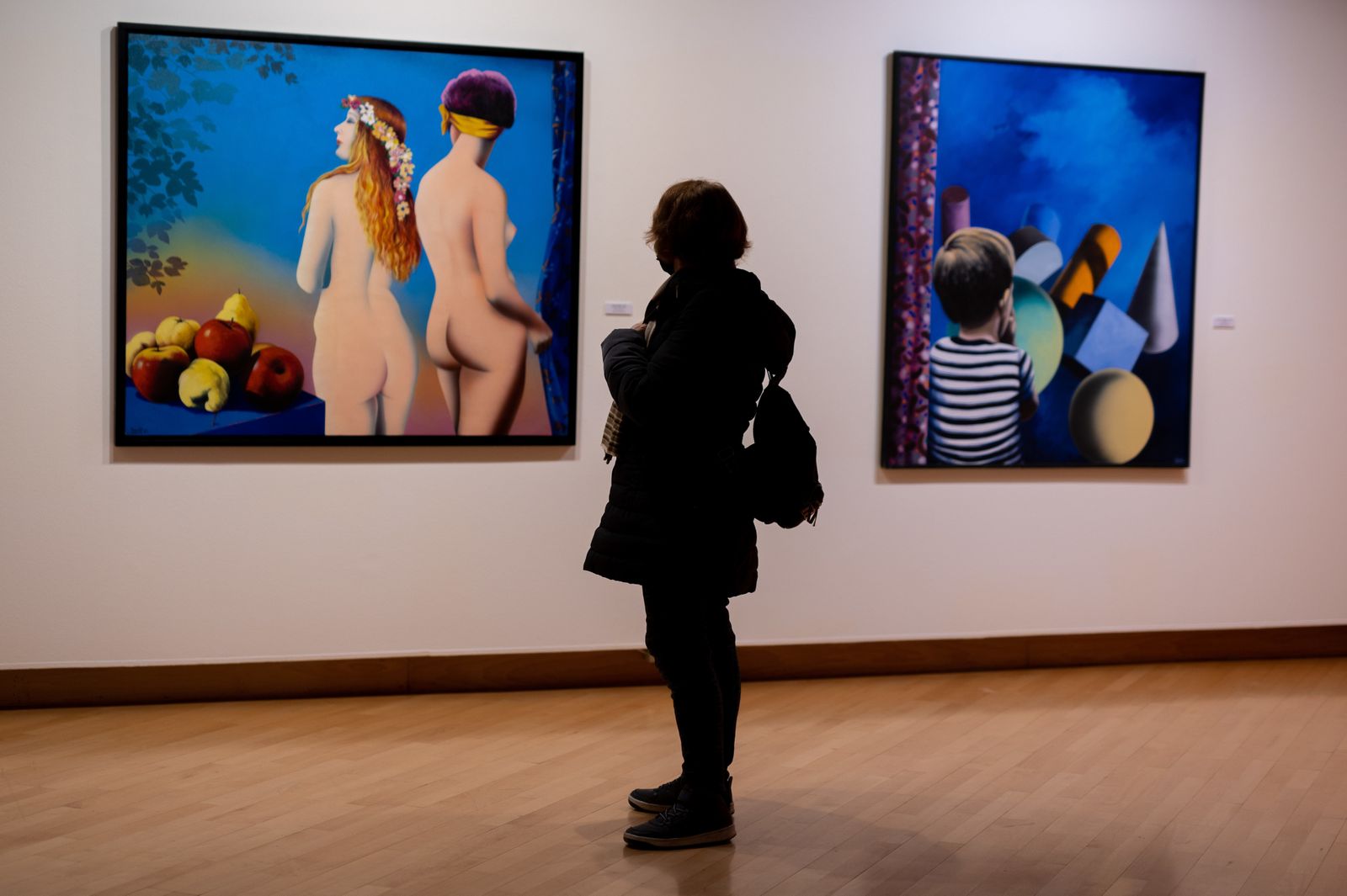 Una mujer ante la obra pictórica de Eduardo Úrculo en el Antiguo Hospital de Santa María la Rica de Alcalá
