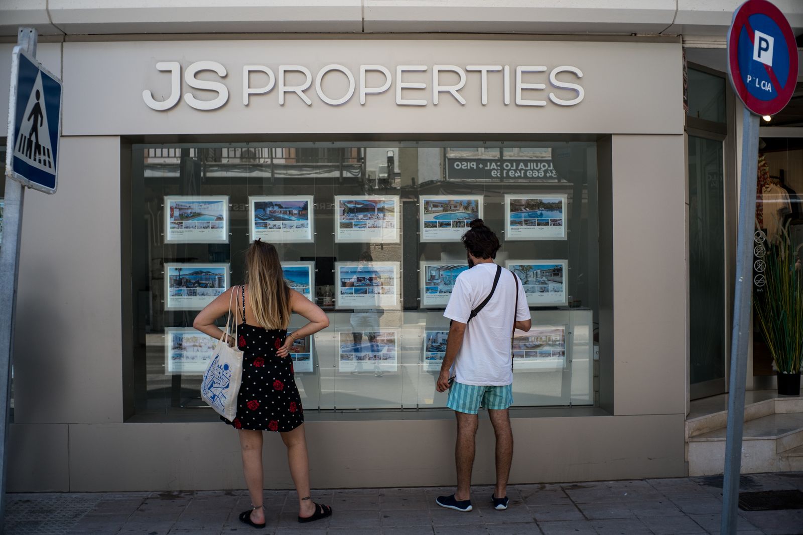 Dos personas observan inmuebles en alquiler y en venta en un escaparate de una inmobiliaria ubicada en Palma de Mallorca
