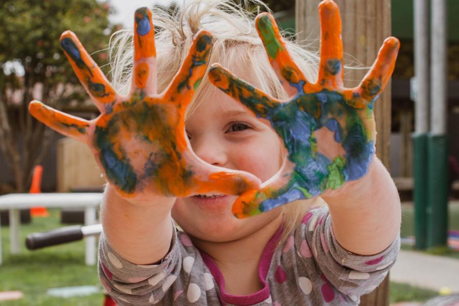 Una niña muestra sus manos llenas de pintura tras una actividad infantil