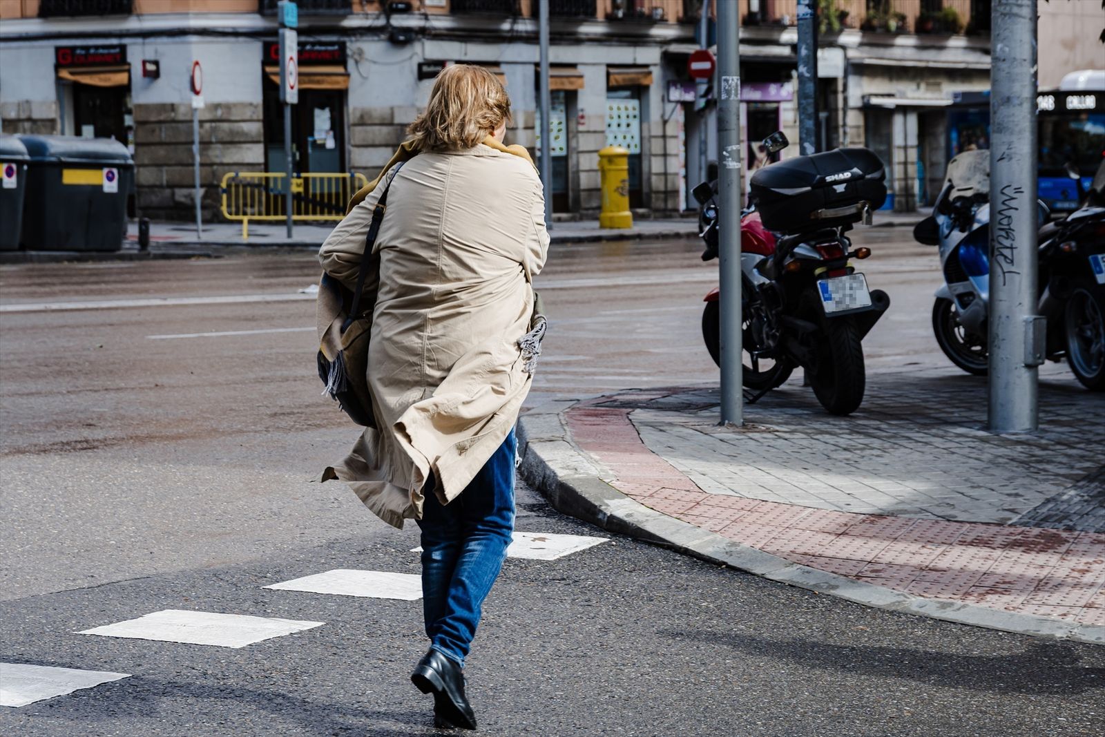 Una mujer cruza una calle de Madrid con viento