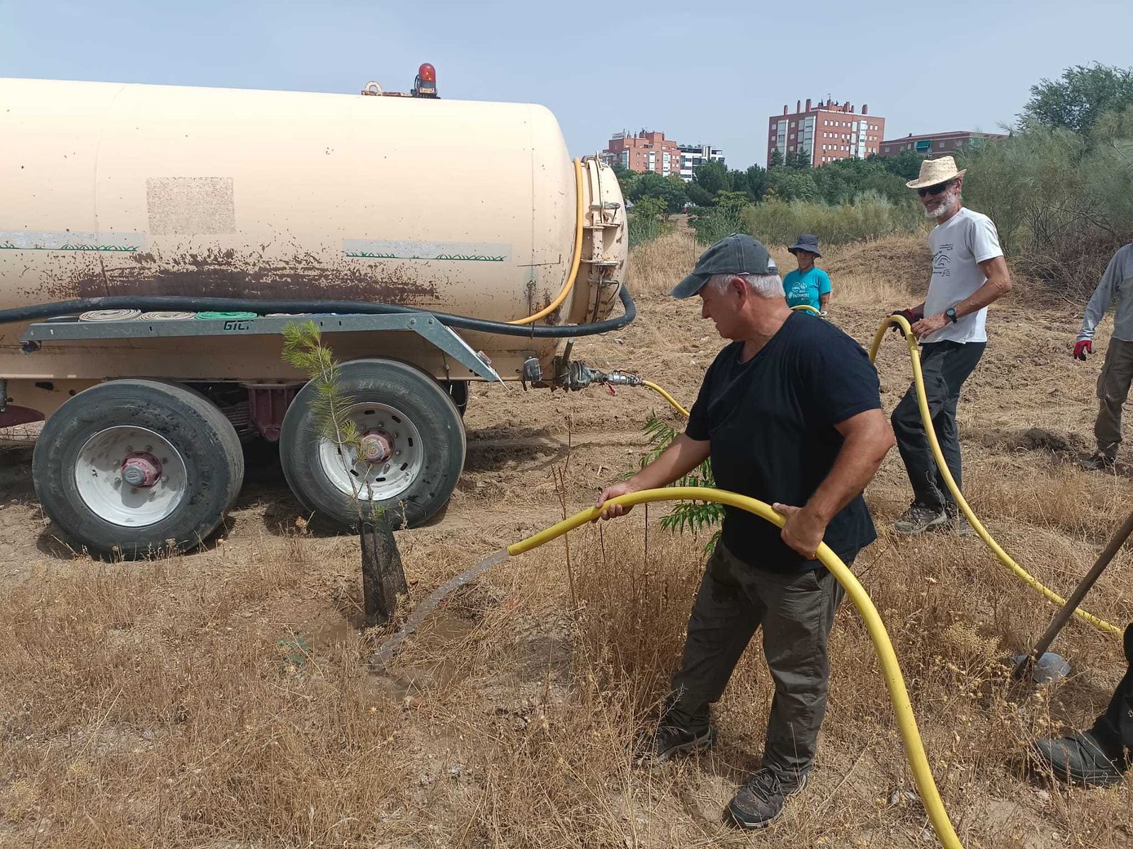 Vecinos de Campamento (Latina) riegan los árboles que han plantado en el Entorno Meaques Retamares