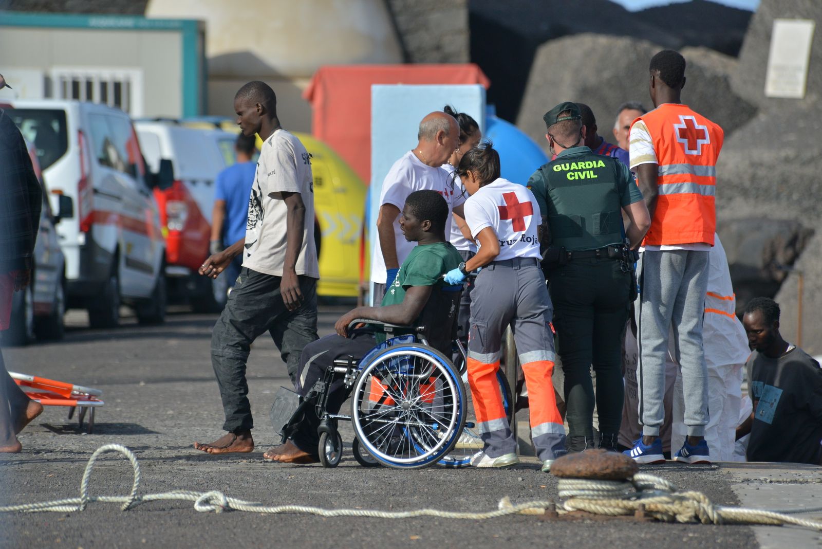 Una trabajadora de la Cruz Roja traslada en silla de ruedas a uno de los migrantes que ha llegado en un cayuco al puerto de La Restinga, a 23 de octubre de 2023, en El Hierro, Santa Cruz de Tenerife, Tenerife, Canarias