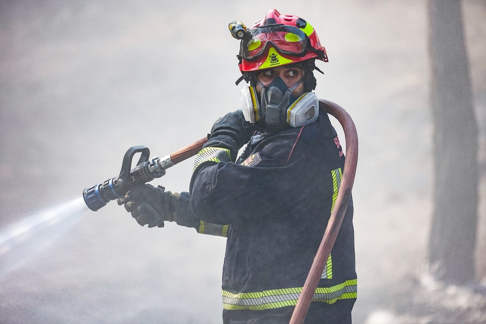 Un bombero de la Comunidad de Madrid sujeta una manguera para extinguir un incendio