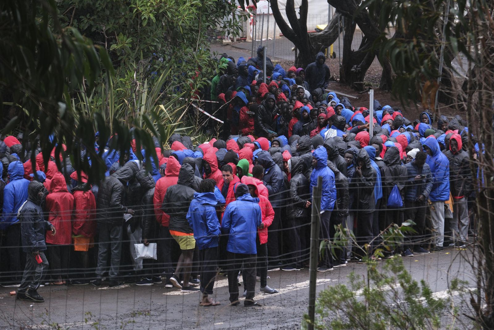Cientos de migrantes de origen subsahariano, en su mayoría senegaleses, hacen fila bajo la lluvia este domingo para acceder al centro de acogida para migrantes de Las Raíces en Tenerife
