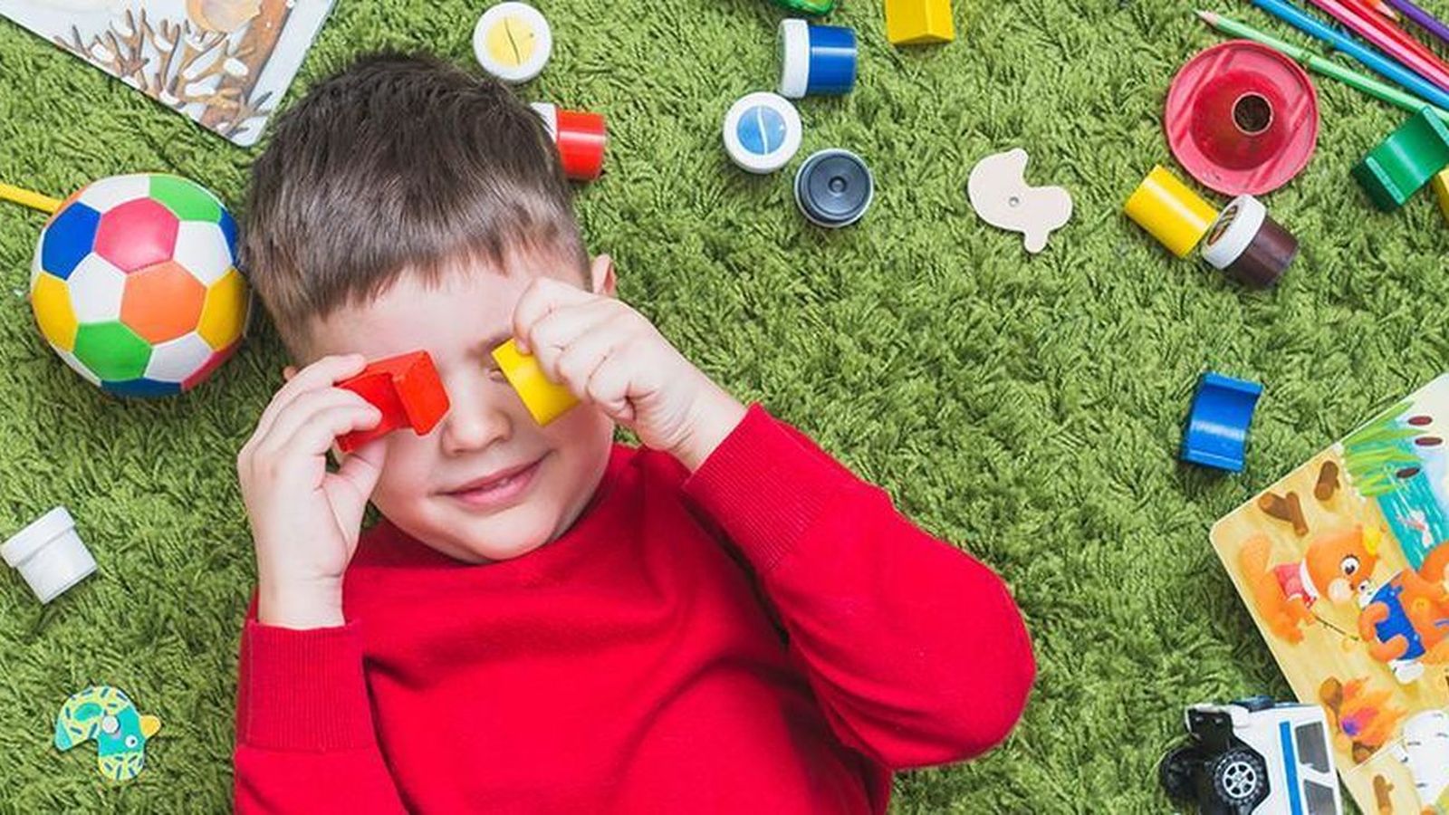 Un niño juega tumbado en el suelo