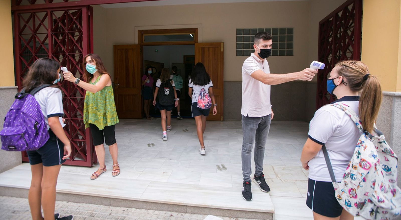 Auxiliares de un instituto toman la temperatura a los alumnos antes de su entrada