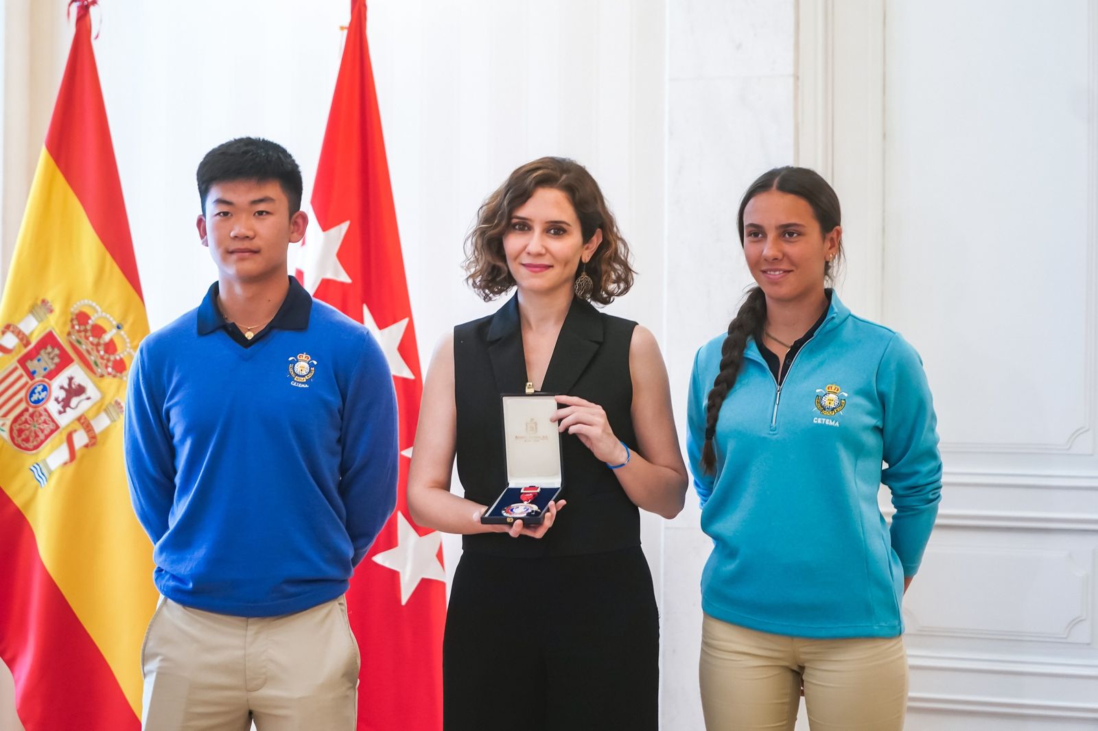 Isabel Díaz Ayudo acompañada por dos jugadores de golf madrileños