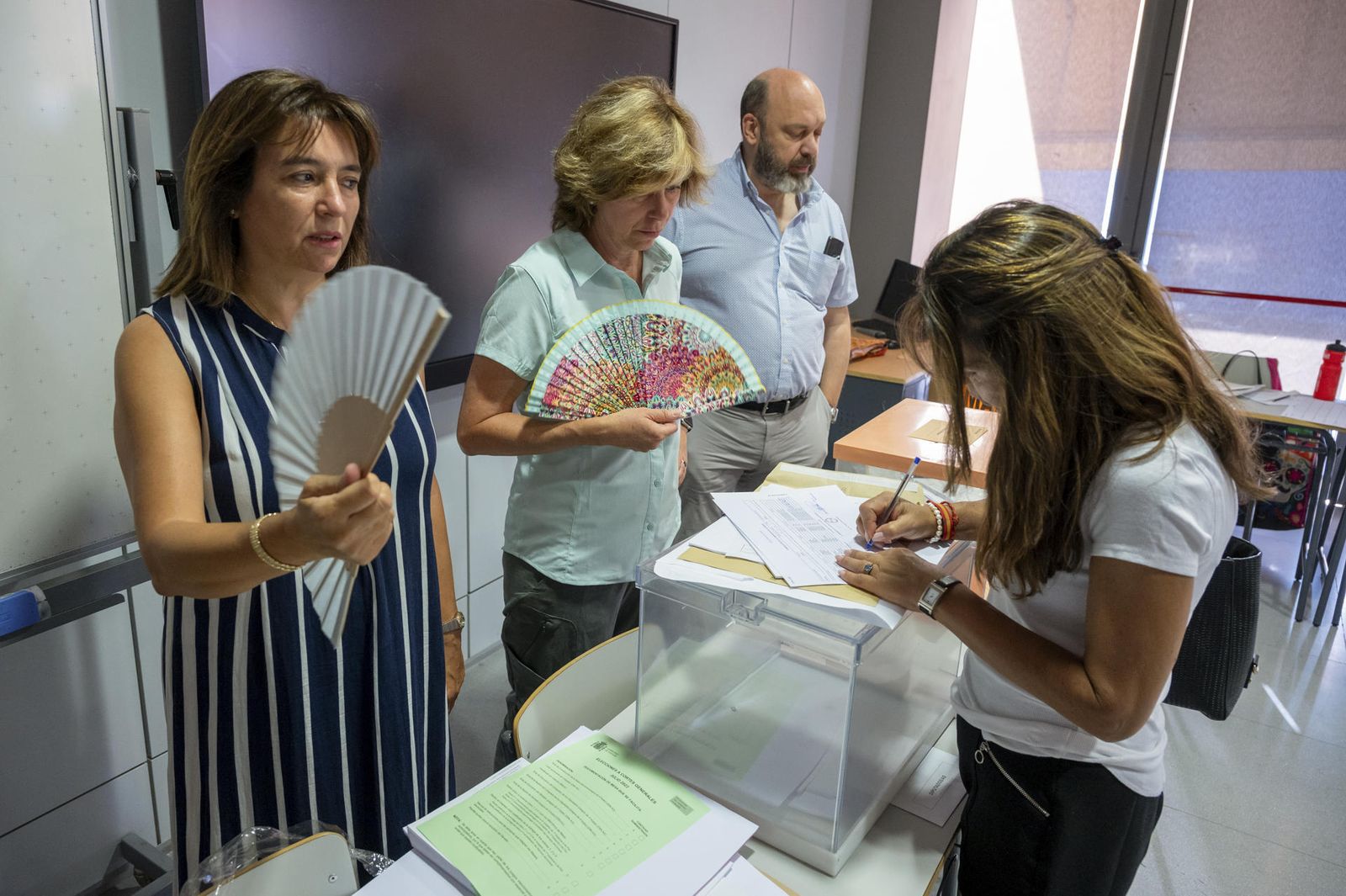 Dos señoras se abanican mientras esperan para depositar su voto