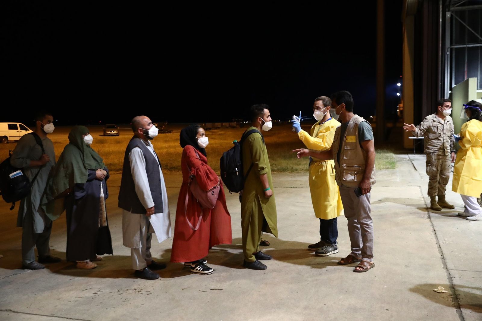 Un sanitario toma la temperatura al grupo de afganos llegados a la base de Torrejón de Ardoz
