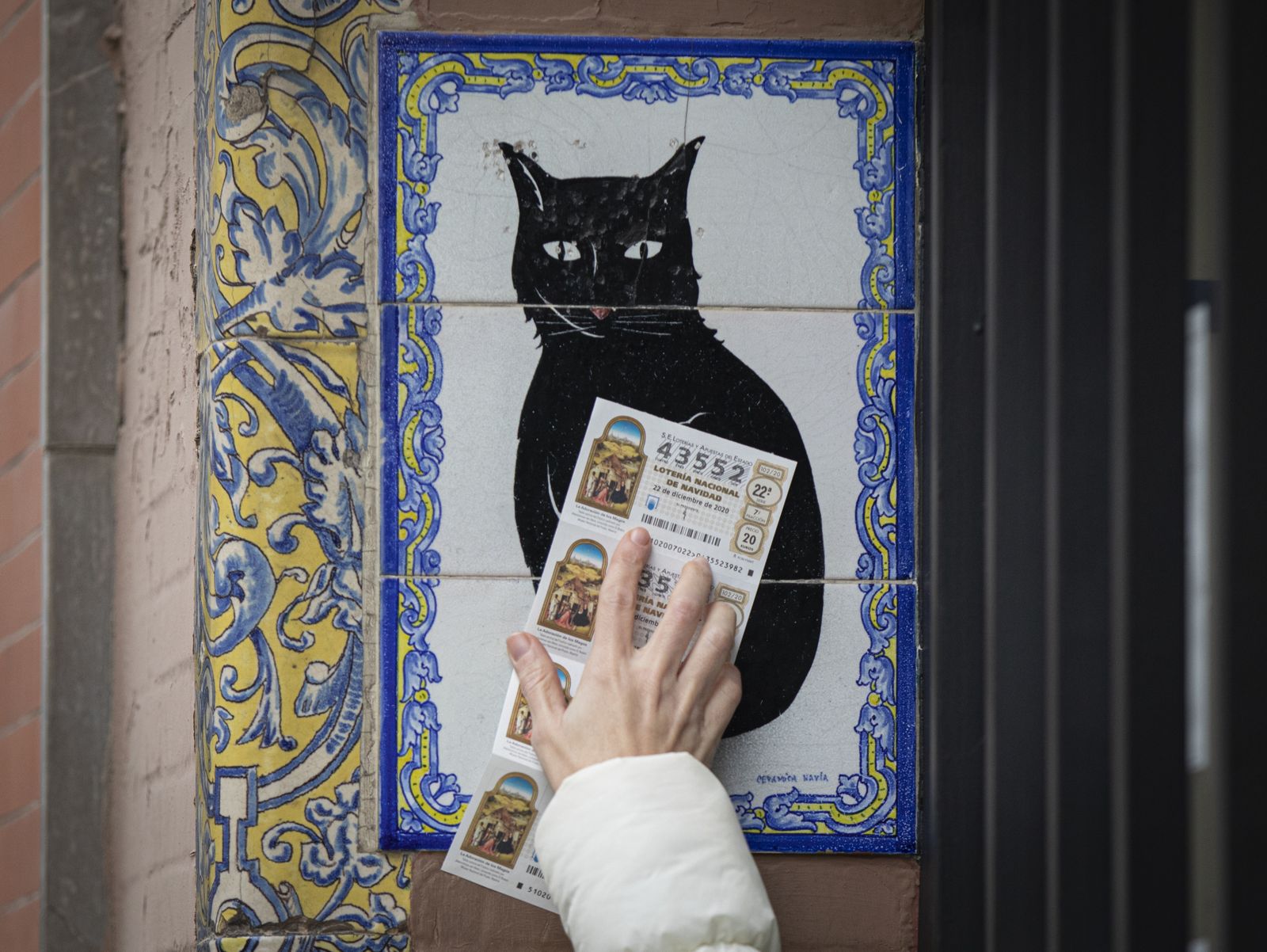 Una persona pasa un décimo de Lotería por azulejo de 'El gato negro'