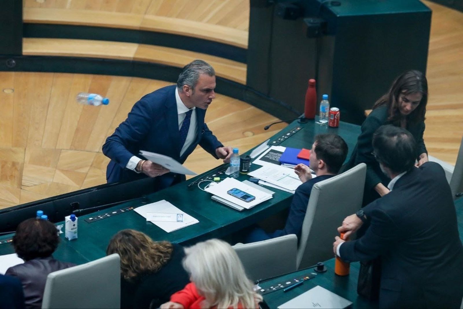 Momento en el que el portavoz de Vox en el Ayuntamiento de Madrid, Javier Ortega Smith, se encara y tira unos papeles y una botella de agua vacía al edil Eduardo Fernández Rubiño, concejal de Más Madrid, en su escaño
