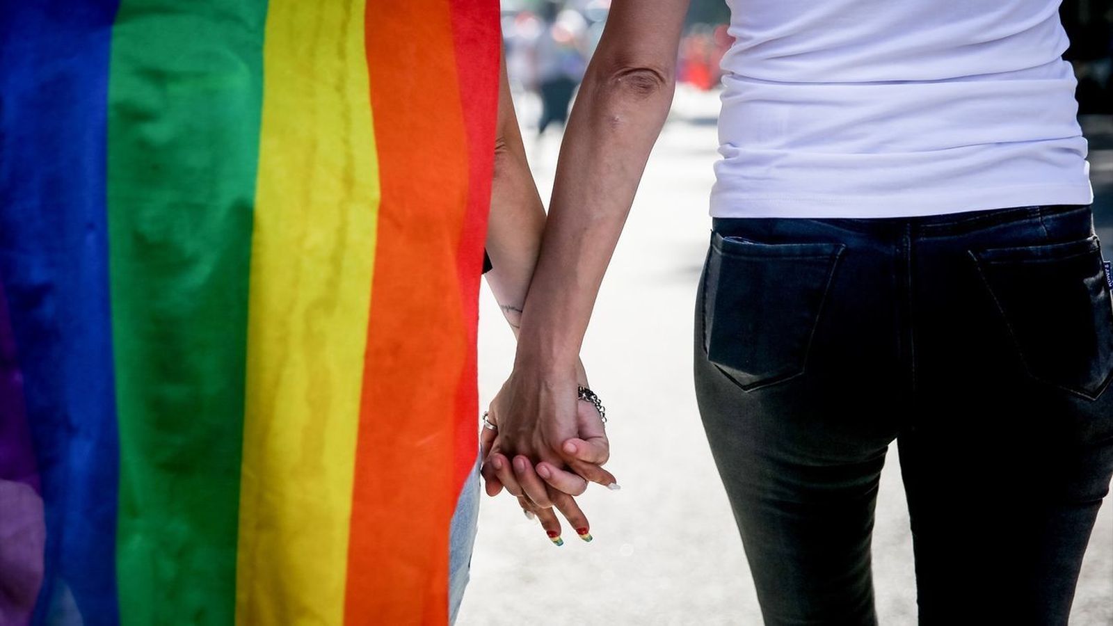 Una pareja pasea con una bandera LGTBI